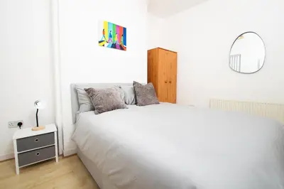 a white bedroom with a large bed and a mirror at Cosy 2BR Flat Near Anfield & Goodison, Liverpool in Liverpool