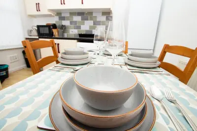 a table with a bowl and plates and wine glasses at Cosy 2BR Flat Near Anfield & Goodison, Liverpool in Liverpool