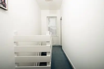 a staircase in a room with white walls at Cosy 2BR Flat Near Anfield & Goodison, Liverpool in Liverpool