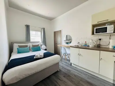 a bedroom with a large bed and a kitchen at Bold Street Studio VIII in Liverpool