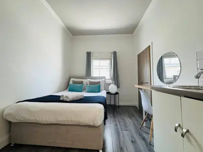 a bedroom with a bed with blue pillows and a sink at Bold Street Studio VIII in Liverpool