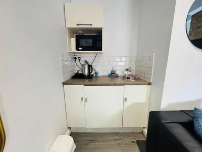 a small kitchen with white cabinets and a microwave at Bold Street Studio VI in Liverpool