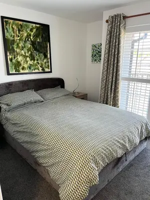 a bed in a bedroom with a large window at 2 Bed Modern Apartment in Haydock