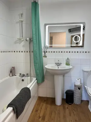 a bathroom with a sink and a bath tub and a mirror at 2 Bed Modern Apartment in Haydock