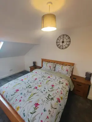 a bedroom with a bed and a clock on the wall at Chic 2-Bed Loft Bungalow, Cleveleys, Near Beach in Blackpool