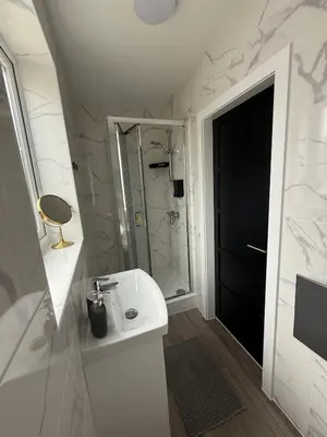 a white bathroom with a sink and a shower at Stylish and Bright 2 Bedroom Flat Free Parking in Wallasey