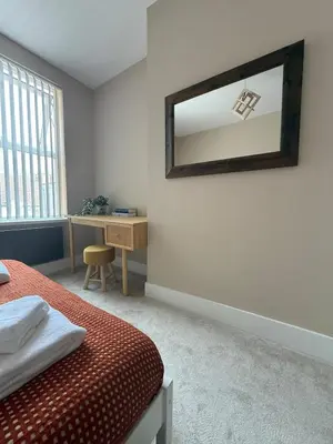 a bedroom with a bed and a mirror on the wall at Stylish and Bright 2 Bedroom Flat Free Parking in Wallasey