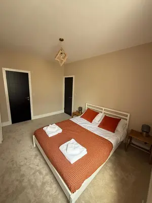 a bedroom with a large bed with two towels on it at Stylish and Bright 2 Bedroom Flat Free Parking in Wallasey