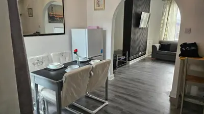 a kitchen with a table with chairs and a refrigerator at A home away- 2 bedrooms in Saint Helens