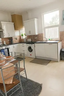 a kitchen with white cabinets and a table and a sink at Cosy Two-Bedroom House in Ormskirk in Pemberton