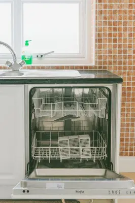 an open dishwasher with dishes in it in a kitchen at Cosy Two-Bedroom House in Ormskirk in Pemberton