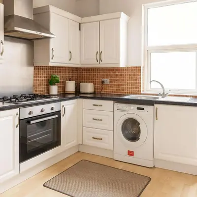 a kitchen with white cabinets and a washing machine at Cosy Two-Bedroom House in Ormskirk in Pemberton