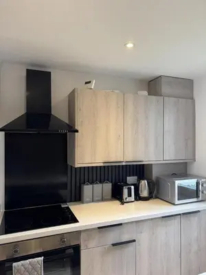 a kitchen with wooden cabinets and a stove top oven at Blackpool Abode - Suites by the Sea in Blackpool