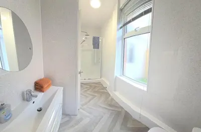 a white bathroom with a sink and a window at Blackpool Abode - Suites by the Sea in Blackpool