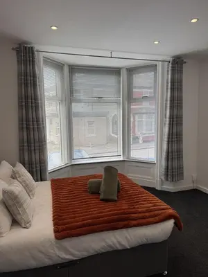 a bedroom with a bed with a blanket and two windows at Blackpool Abode - Suites by the Sea in Blackpool