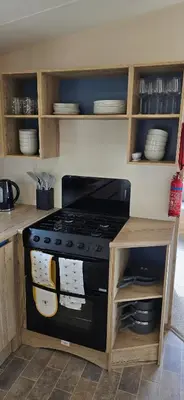 a kitchen with a stove and shelves with dishes at Lakeland leisure park sleeps up to 8 in Cark