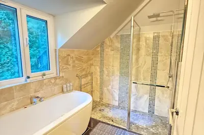 a bathroom with a tub and a glass shower at 4 Bed Retreat-Sleeps 7-Parking-Garden-Lake Views in Bolton
