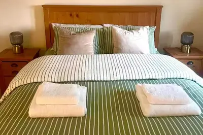 a bed with two towels on top of it at 4 Bed Retreat-Sleeps 7-Parking-Garden-Lake Views in Bolton