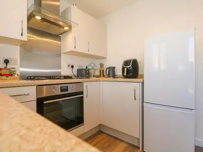 a kitchen with white cabinets and a white refrigerator at Beach House Seaside Dunes in Lytham St Annes