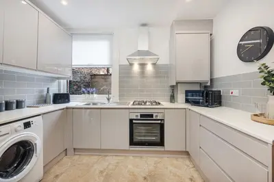 a kitchen with white cabinets and a washer and dryer at Onslow House - Air Host & Stay - 5 bed, Sleeps 14 in Liverpool
