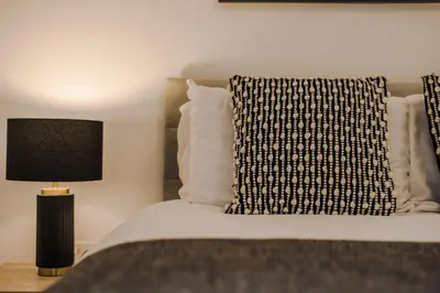 a bed with a black and white pillow and a lamp at Onslow House - Air Host & Stay - 5 bed, Sleeps 14 in Liverpool