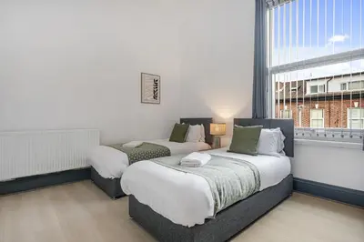 two beds in a room with a window at Onslow House - Air Host & Stay - 5 bed, Sleeps 14 in Liverpool