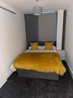 a bedroom with a bed with a yellow blanket on it at Modern City Centre Apartment in Liverpool