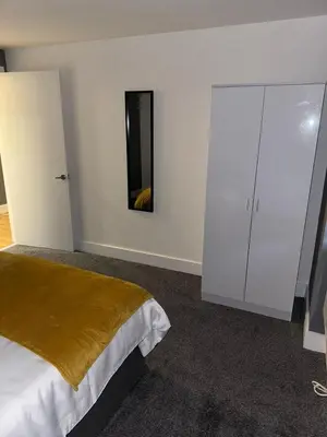a bedroom with a bed and a white cabinet at Modern City Centre Apartment in Liverpool