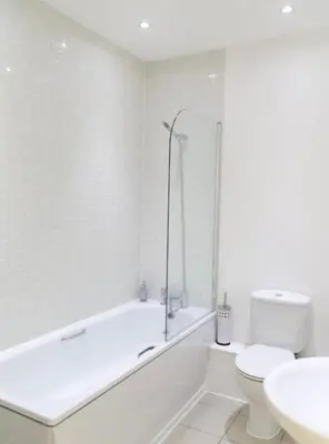 a bathroom with a tub and a toilet and a sink at Modern City Centre Apartment in Liverpool