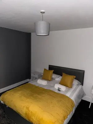 a bedroom with a large bed with two yellow pillows at Modern City Centre Apartment in Liverpool