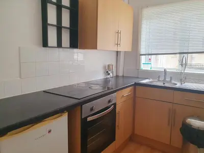 a kitchen with wooden cabinets and a black counter top at Holiday flat first floor in Blackpool