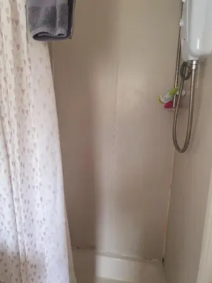 a shower with a white shower curtain and a shower head at Holiday flat first floor in Blackpool