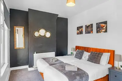 a bedroom with a large bed with two gold rings on the wall at Modern 2-Bedroom Contractor House with 4 Beds, Free Parking, High-Speed Wi-Fi in Seacombe