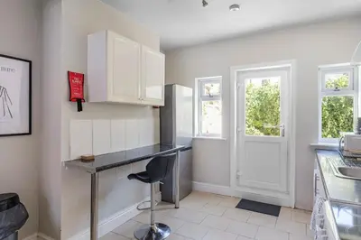 a kitchen with white cabinets and a black counter top at Modern 2-Bedroom Contractor House with 4 Beds, Free Parking, High-Speed Wi-Fi in Seacombe