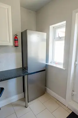 a stainless steel refrigerator in a kitchen with a window at Modern 2-Bedroom Contractor House with 4 Beds, Free Parking, High-Speed Wi-Fi in Seacombe