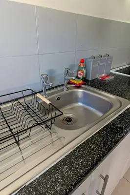 a kitchen sink with a metal grate on it at Modern 2-Bedroom Contractor House with 4 Beds, Free Parking, High-Speed Wi-Fi in Seacombe