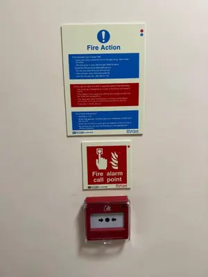 a fire action sign is hanging on a wall at 2-Bedroom Flat Near River Lune in Halton