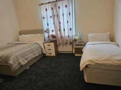 a bedroom with two beds and a window with curtains at Modern Seaside Stay at Bela Grove-Sleeps8 in Blackpool