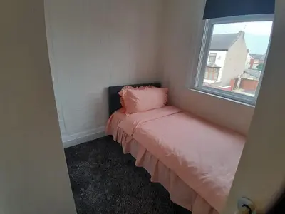 a small room with a bed with a window at Modern Seaside Stay at Bela Grove-Sleeps8 in Blackpool