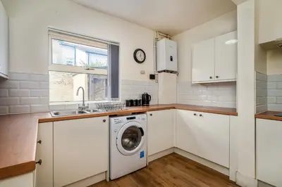 a kitchen with white cabinets and a washing machine at Birkenhead Haven - Sleeps 14 - Family and Group Stay in Birkenhead