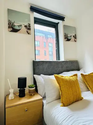 a bed with yellow and white pillows and a window at 2 Bedroom City Centre Apartment Free Secure Parking in Liverpool