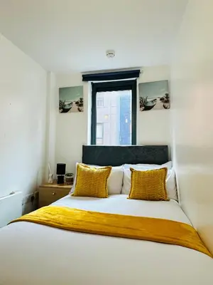 a bedroom with a bed with yellow pillows and a window at 2 Bedroom City Centre Apartment Free Secure Parking in Liverpool