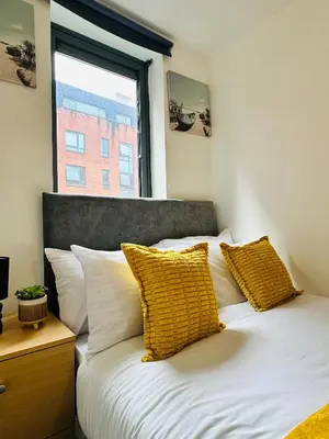 a bedroom with a bed with yellow pillows and a window at 2 Bedroom City Centre Apartment Free Secure Parking in Liverpool