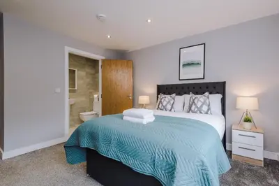 a bedroom with a large bed and a bathroom at Spacious City Centre 2 Beds 2 baths Sleeps 10 in Liverpool