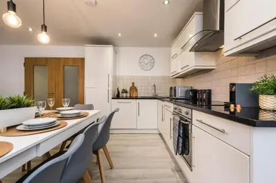 a kitchen with white cabinets and a table and chairs at Spacious City Centre 2 Beds 2 baths Sleeps 10 in Liverpool
