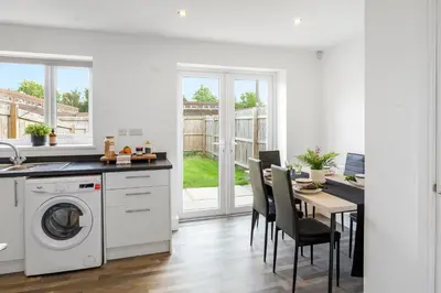 a kitchen with a washing machine and a table with chairs at Quiet St Helens Home Near Train Station, Free Parking and WiFi in Saint Helens