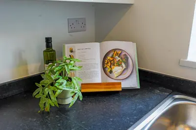a book on a counter with a plant and a bottle of wine at Quiet St Helens Home Near Train Station, Free Parking and WiFi in Saint Helens