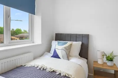 a small bedroom with a bed and a window at Quiet St Helens Home Near Train Station, Free Parking and WiFi in Saint Helens