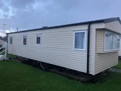 a small white trailer sitting in the grass at Seaside Retreat in Fleetwood in Fleetwood