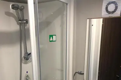 a shower in a bathroom with a sign on the wall at Seaside Retreat in Fleetwood in Fleetwood